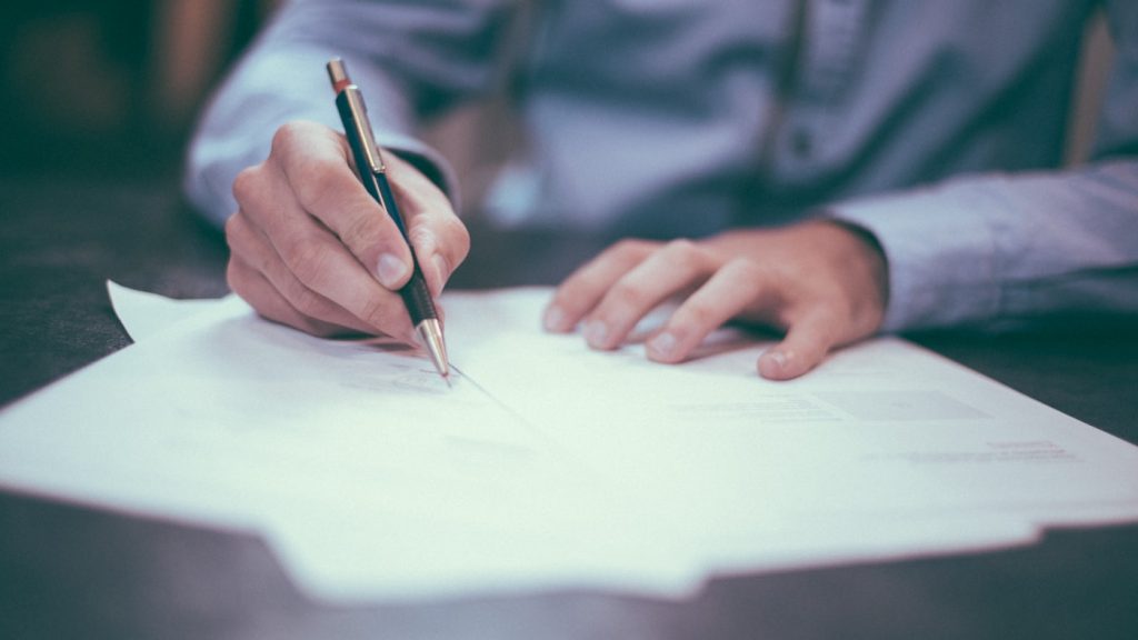 Business owner reviewing cyber insurance renewal paperwork on desk with calculator and notebook