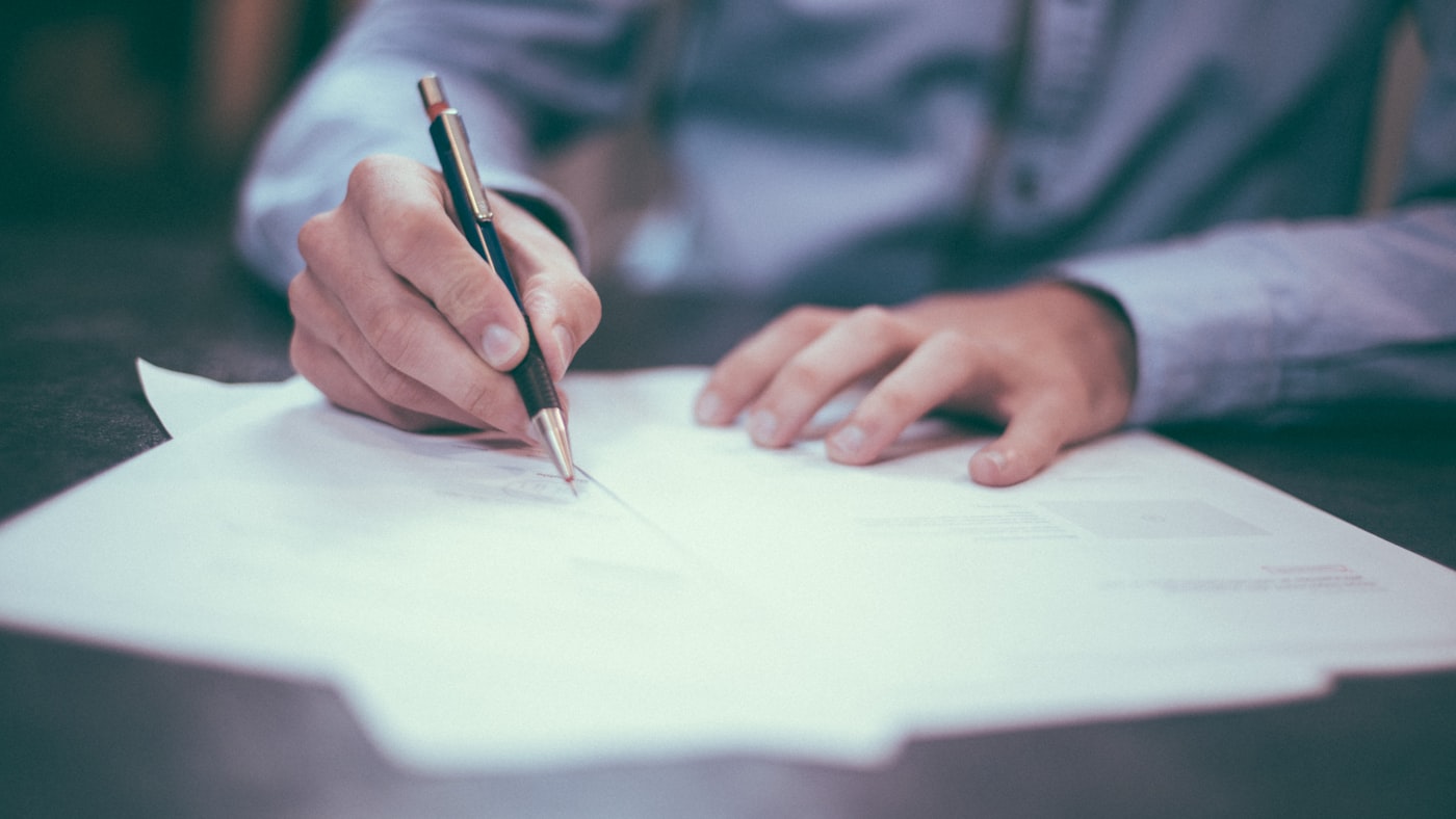 Business owner reviewing cyber insurance renewal paperwork on desk with calculator and notebook